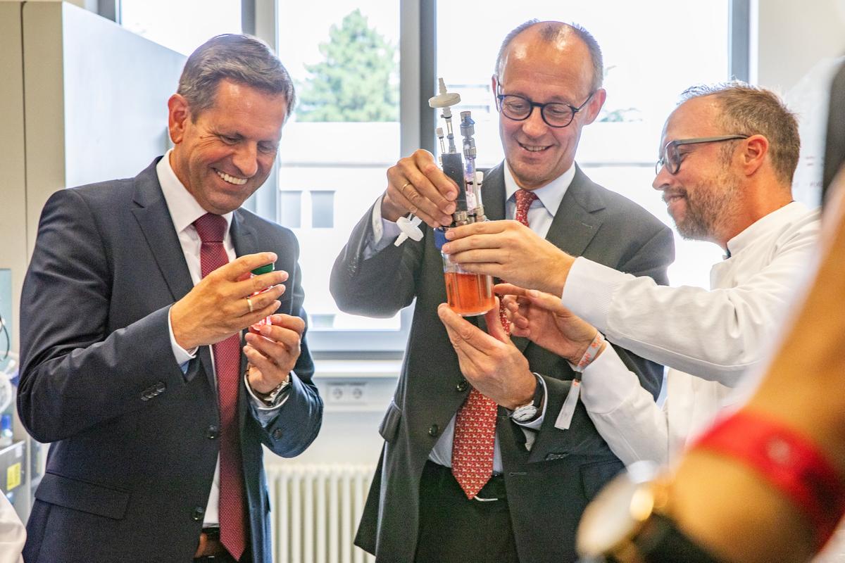 Nico Lachmann zeigt Bundeskanzler Friedrich Merz und Ministerpräsident Olaf Lies einen Bioreaktor.