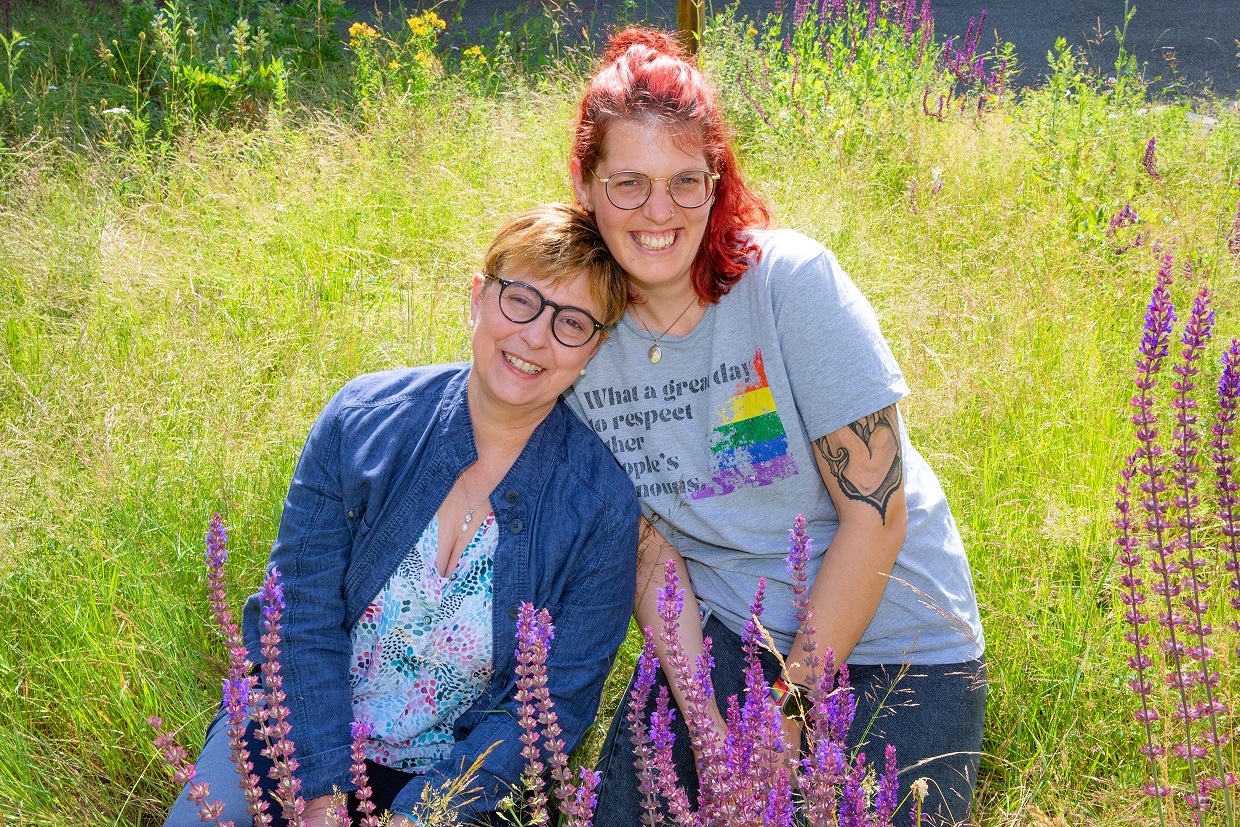 Susanne Klyk und Anjan Pengel sitzen nebeneinander auf einer grünen Wiese. 