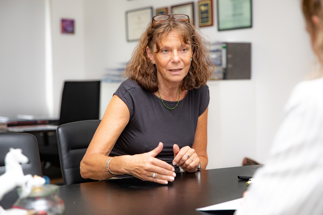 Professorin Hilfiker-Kleiner sitzt an einem Schreibtisch und spricht mit einer Person ihr gegenüber