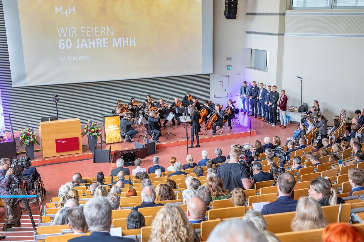 Blick von oben in den Hörsaal F, in dem der Festakt 60 Jahre MHH stattfindet. Viele Meschen sitzen in den Reihen, vorne spielt ein Orchester.