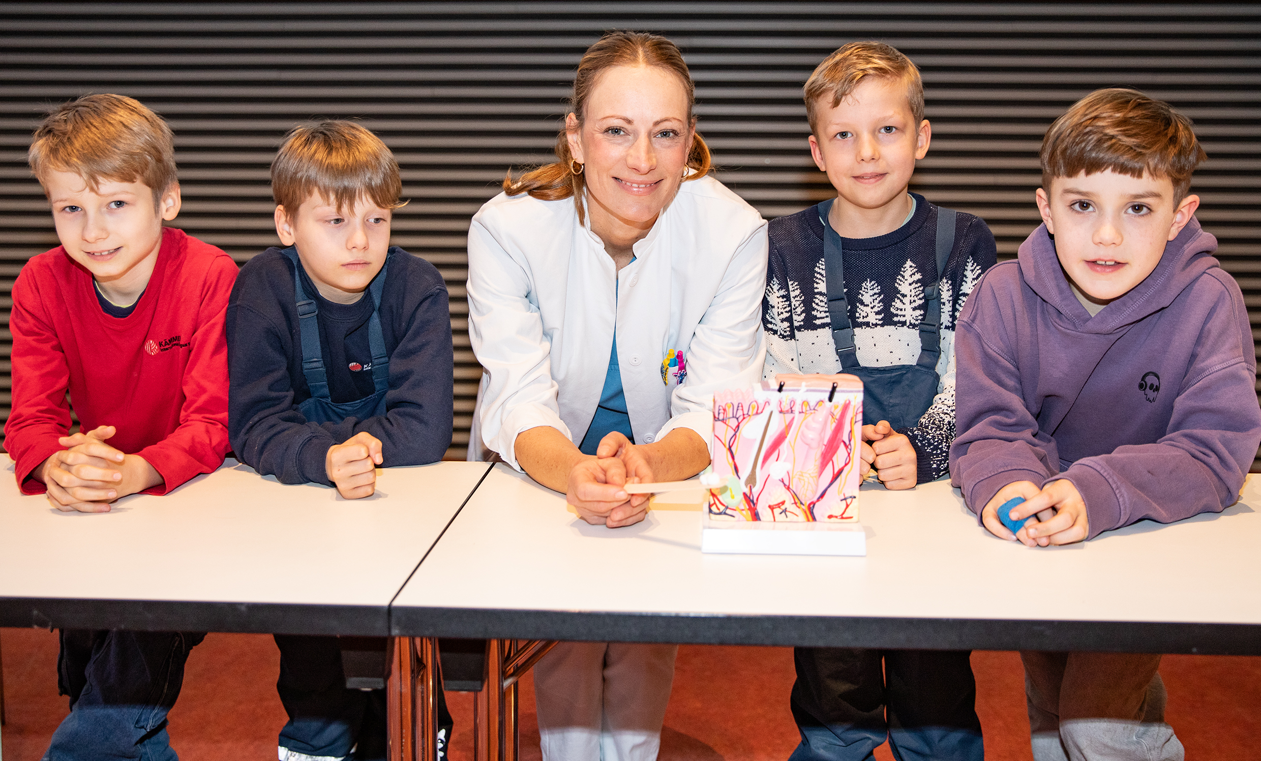 Dr. Eva Moennig umringt von vier Kinder bei der KinderUni-Vorlesung im Hörsaal F.