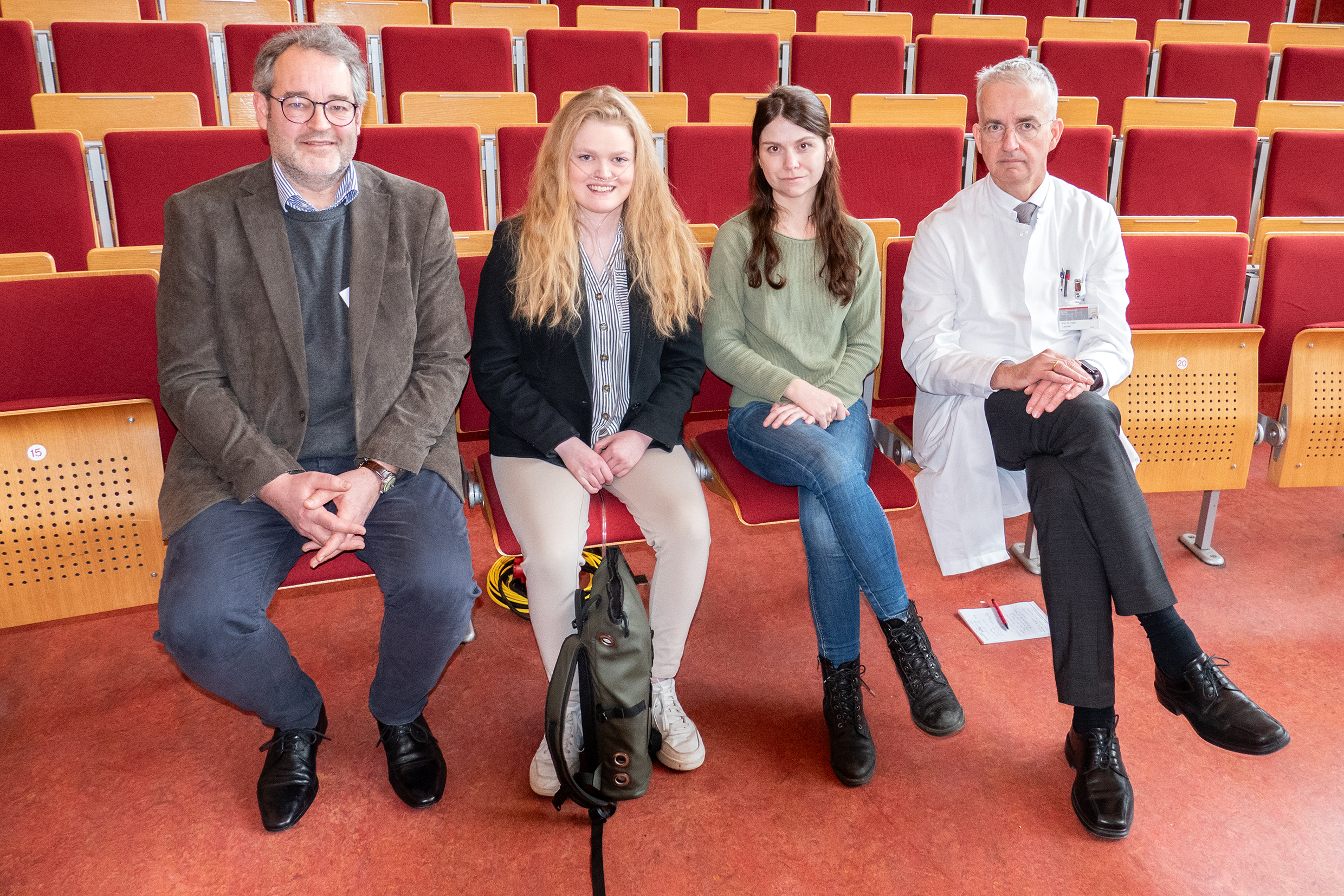 India Heilmann und Lina Rosenboom (2.v. re.) sitzen mit Prof. Dr. Christian Mühlfeld (links) und Prof. Dr. Frank Lammert (rechts) in einer Stuhlreihe eines Hörsaals.