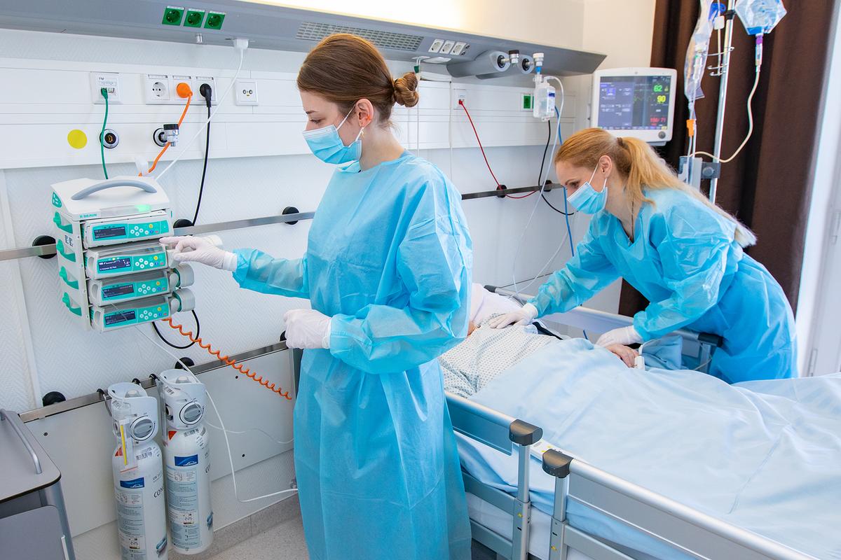 Two female nurses are standing by a hospital bed