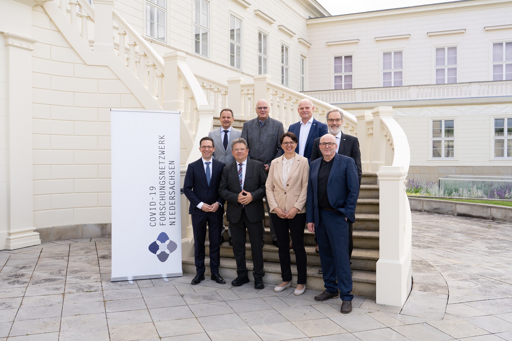 Gruppenbild mit Teilnehmenden des COFONI-Abschlusssymposiums auf einer Treppe vor dem Tagungszentrum Schloss Herrenhausen. 