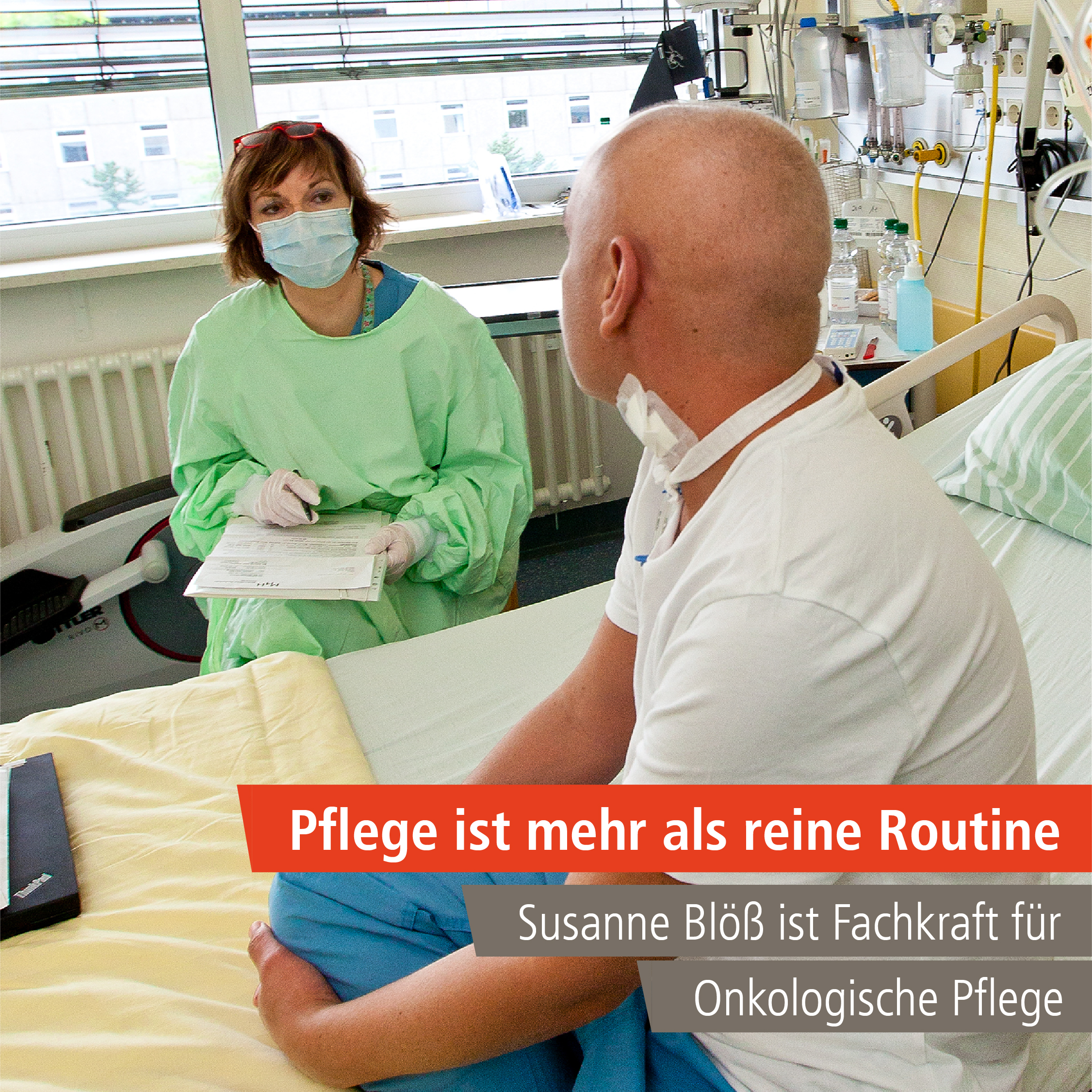 Frau sitzt in Schutzkleidung und mit Maske an einem Patientenbett und hat einen Notizblock auf den Knien. Patient sitzt mit Rücken zur Kamera auf einem Krankenbett.