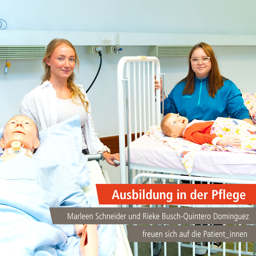 Marleen Schneider und  Rieke Busch-Quintero Dominguez stehen an zwei Betten mit  Puppen als Übungsdummys