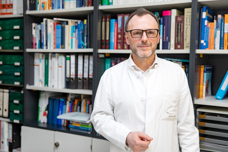 Ein Foto von Prof. Kahl in seinem Arbeitszimmer. Hinter ihm stehen sehr viele Bücher im Regal.