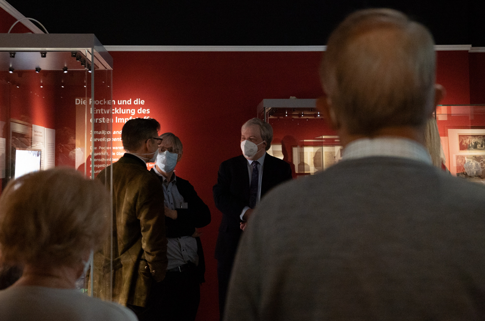 Kurator Oliver Gauert erzählt den BesucherInnen in einem rot gestrichenen Raum etwas über Pocken.