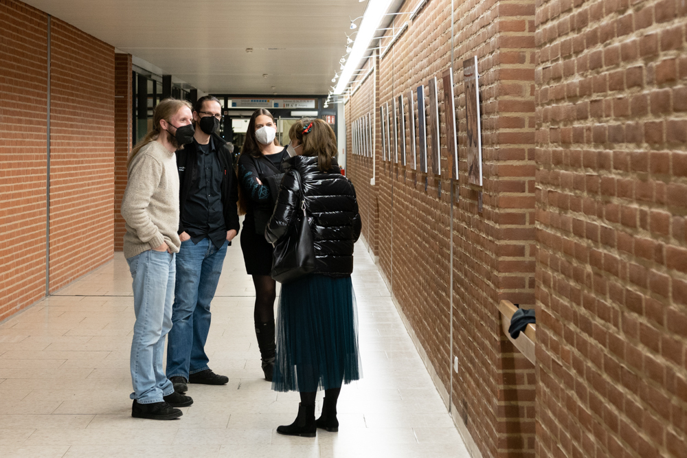 Besucher stehen mit dem Künstler vor seinen Bildern und unterhalten sich mit ihm.