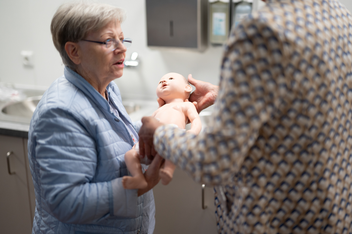 Eine Frau überreicht einer anderen Frau eine Babypuppe