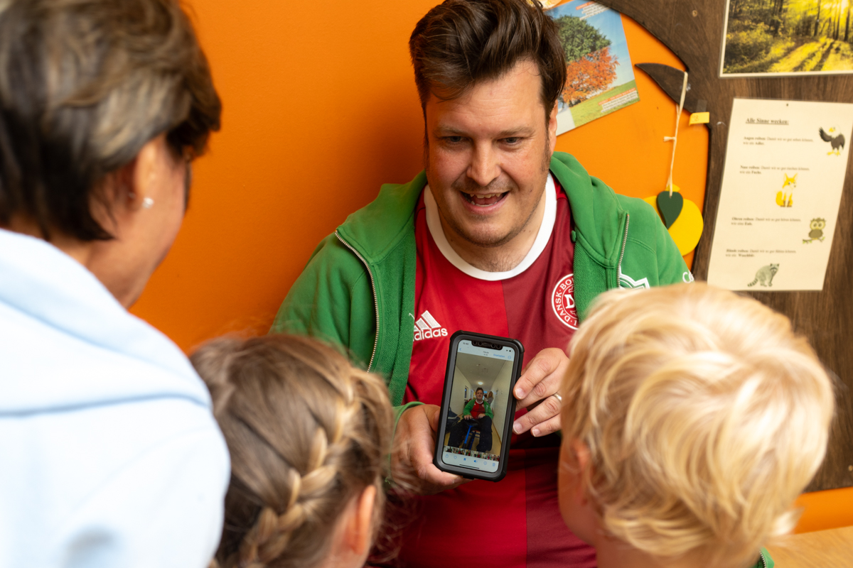 Sven Kamin zeigt den Kindern das fertige Video auf seinem Handy.