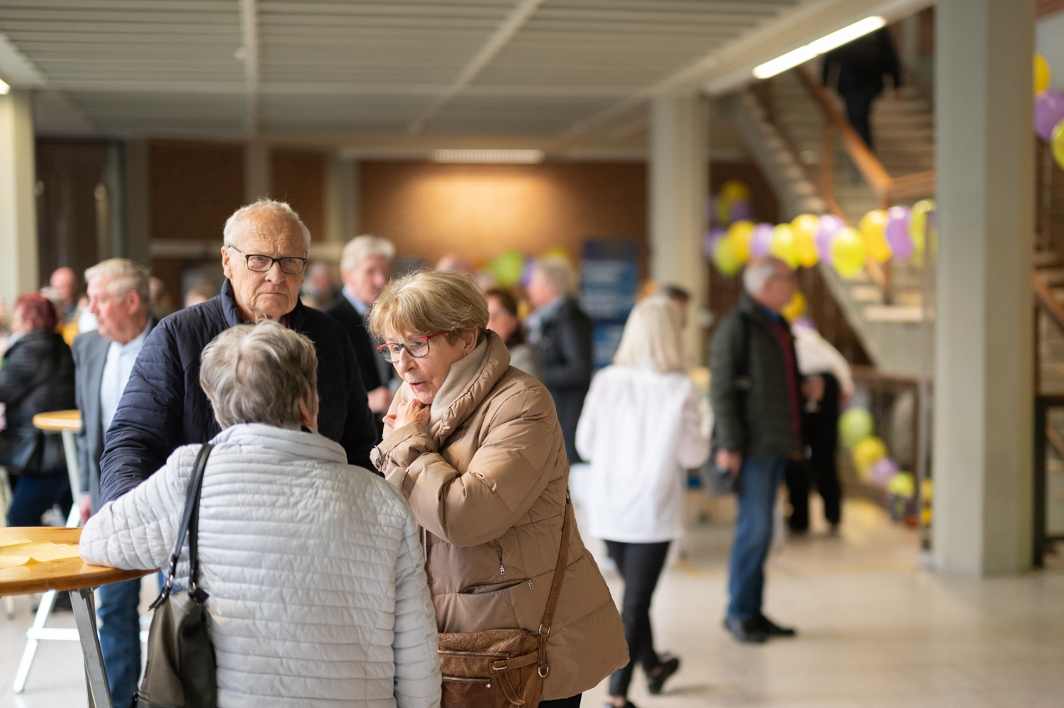 Besucher:innen unterhalten sich an Stehtischen im Flurbereich.