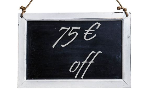 Eine schwarze Tafel mit einem weißen Rahmen ist mit zwei Seilen an der Seite aufgehängt. Auf der Tafel steht in weiß 75 Euro off.
