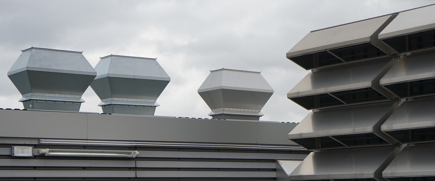 Das Bild zeigt silberne Schornsteine vor einem grau bewölkten Himmel auf einem Flachdach eines MHH-Gebäudes. Copyright: Müller, Jörg/TGM/MHH