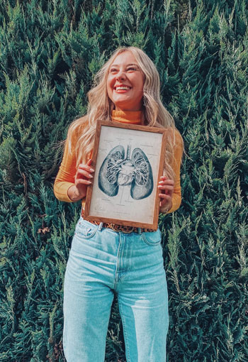 Alina hält ein gerahmtes Bild einer Lunge in den Händen und lacht. / Copyright: Alina Diedrichs