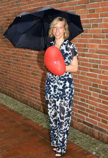 Mareike mit einem schwarzen Regenschirm und einem roten Herzluftballon in der Hand. Copyright: privat