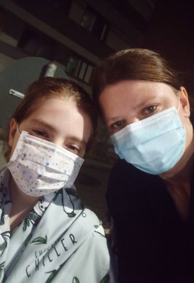 Lara mit ihrer Mutter, beide tragen einen Mundschutz. Copyright: privat