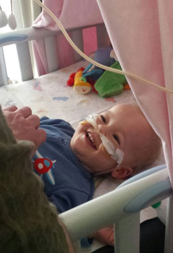 Henry vier Wochen nach der Transplantation. Er liegt im Patientenbett und lacht. / Copyright: Nadine Wolf