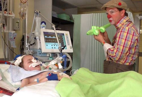 Marius auf der Kinderintensivstation 67, neben ihm steht ein Clinic Clown. Copyright: privat