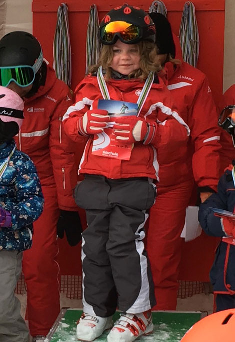 Rebecca steht auf einem Siegerpodest. Sie gewinnt die Goldmedaille bei ihrem ersten Skikurs. Copyright: privat