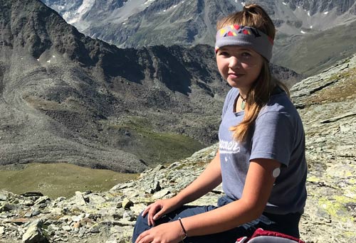 Die lungentransplantierte Xenia sitzt auf einem Berg und macht Pause von ihrer Wanderung