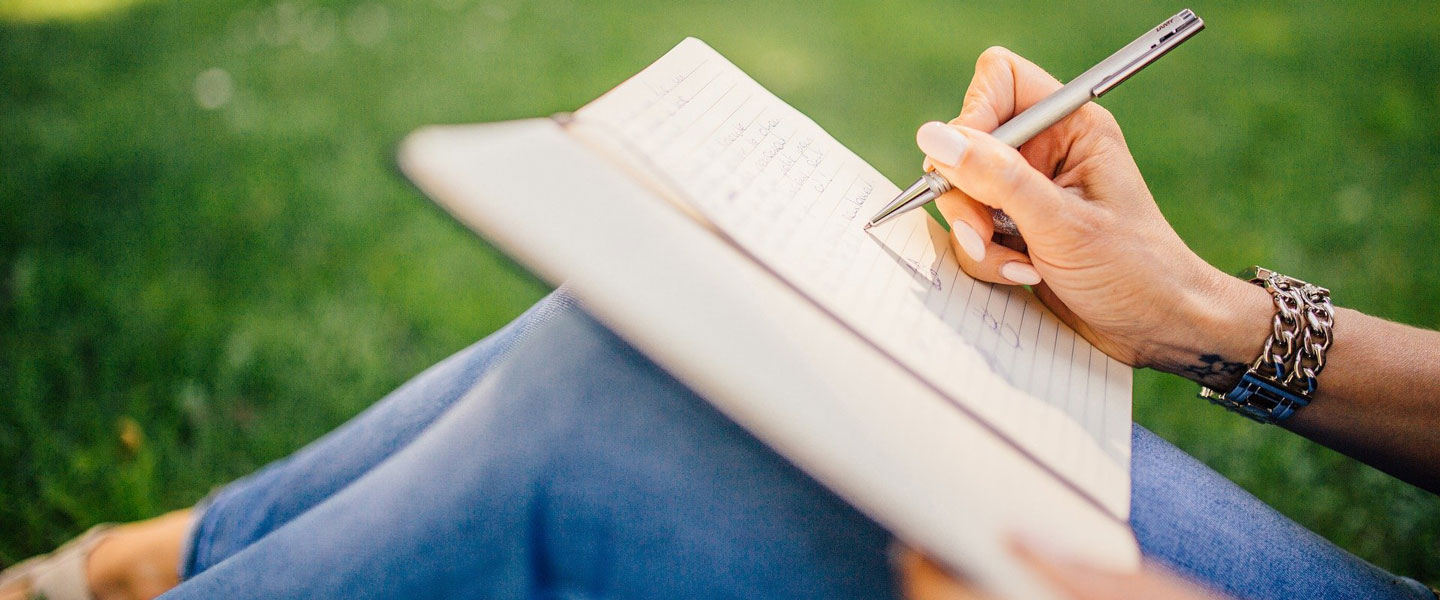 Eine Frauenhand hält einen Stift und schreibt etwas in ein Buch. Copyright: Pixabay/StockSnap. 