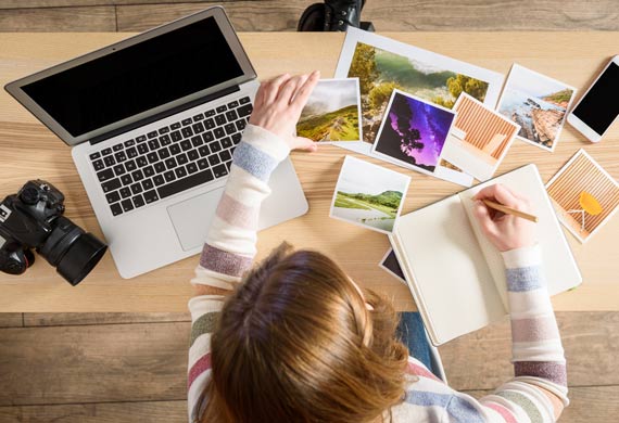 Ein Mädchen sortiert Polaroidfotos und macht sich Notizen; Copyright: iStock/pepmiba