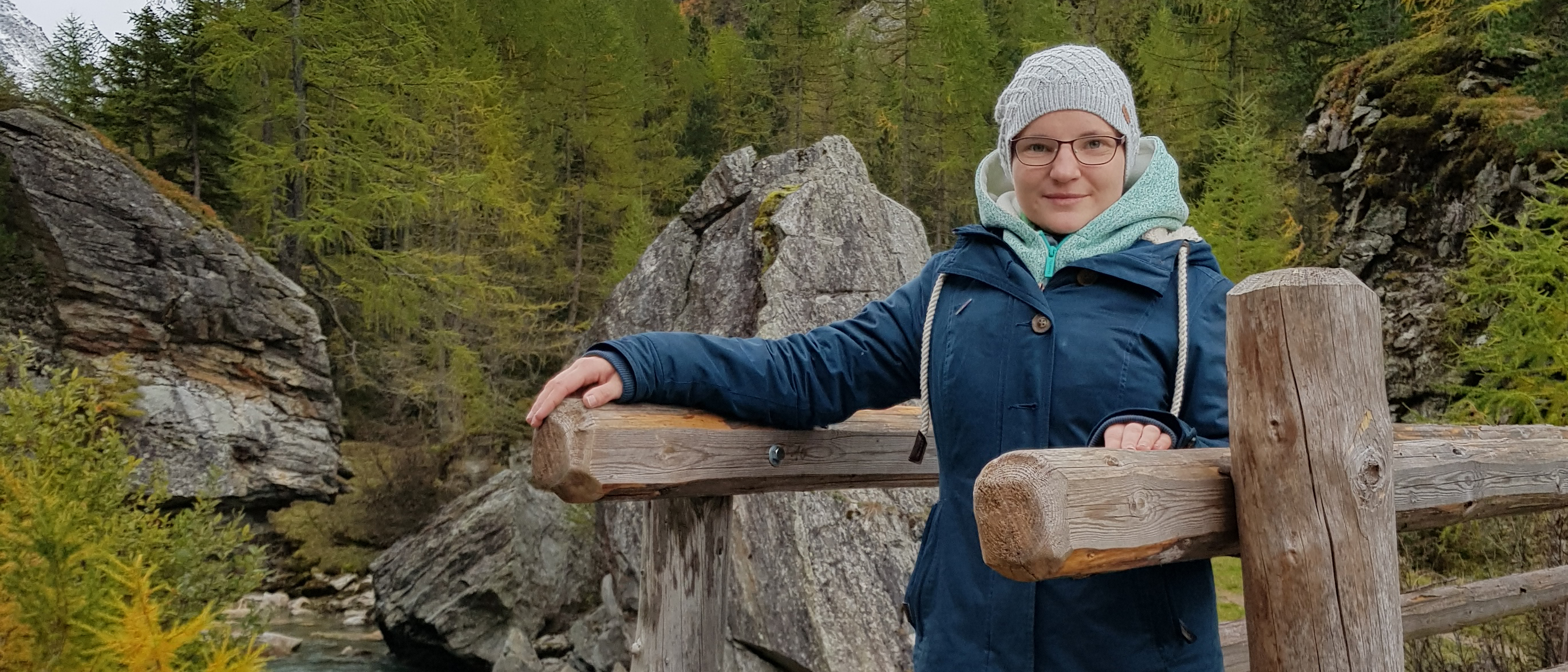 Juliane Brauner steht am Anfang einer Brücke, die über einen Gebirgsbach führt.  Copyright: Juliane Brauner