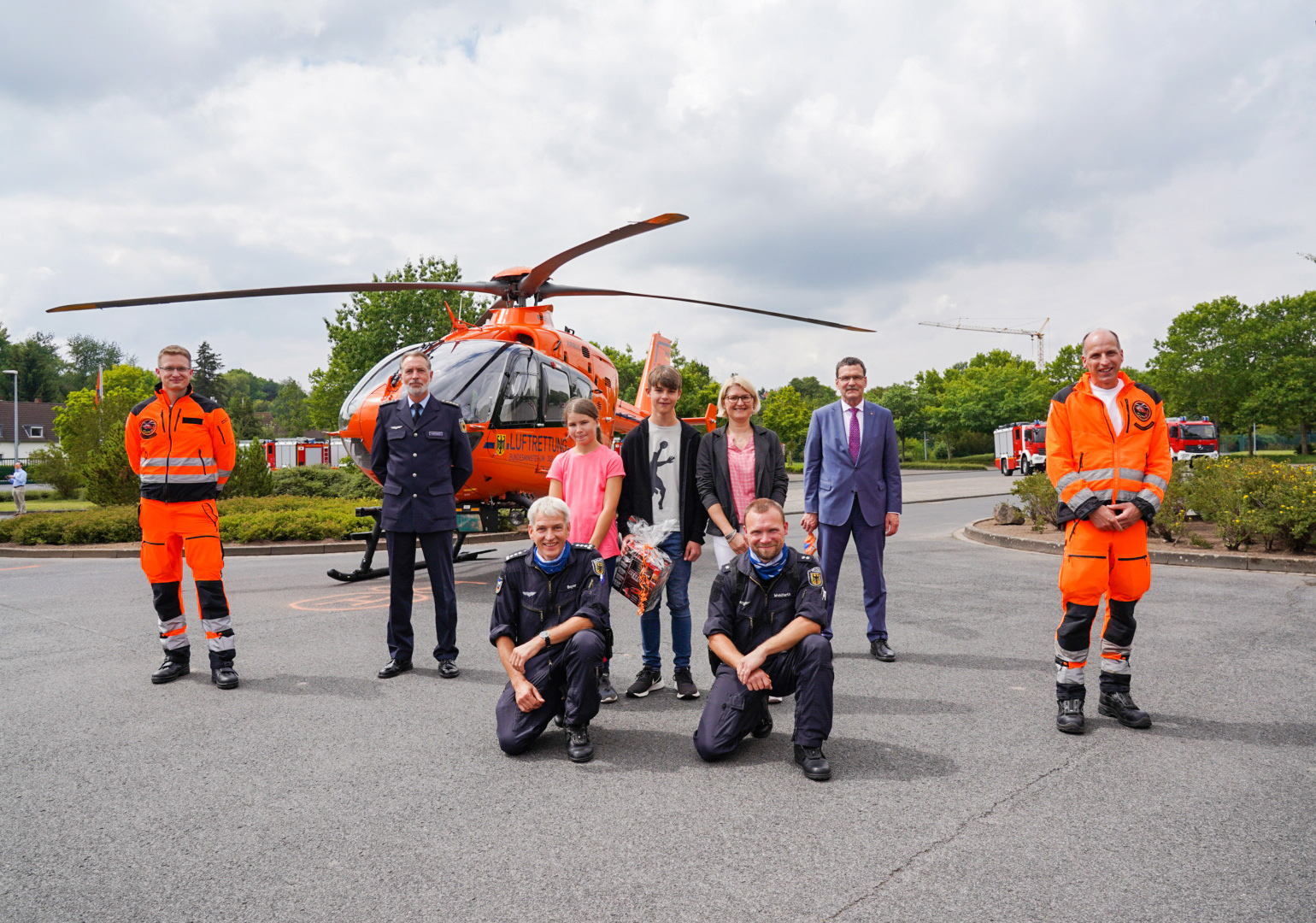 Die Besatzung des Rettungshubschraubers steht mit einem geretteten Patienten vor dem Hubschrauber Christoph 4