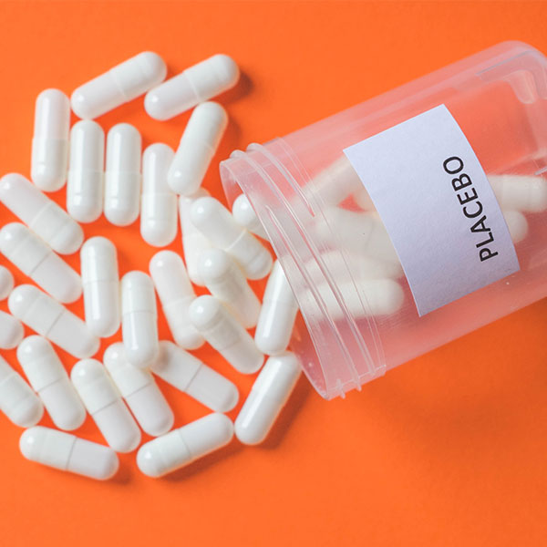 Aus einer Dose, aus der weiße Pillen herausfallen, steht "Placebo"