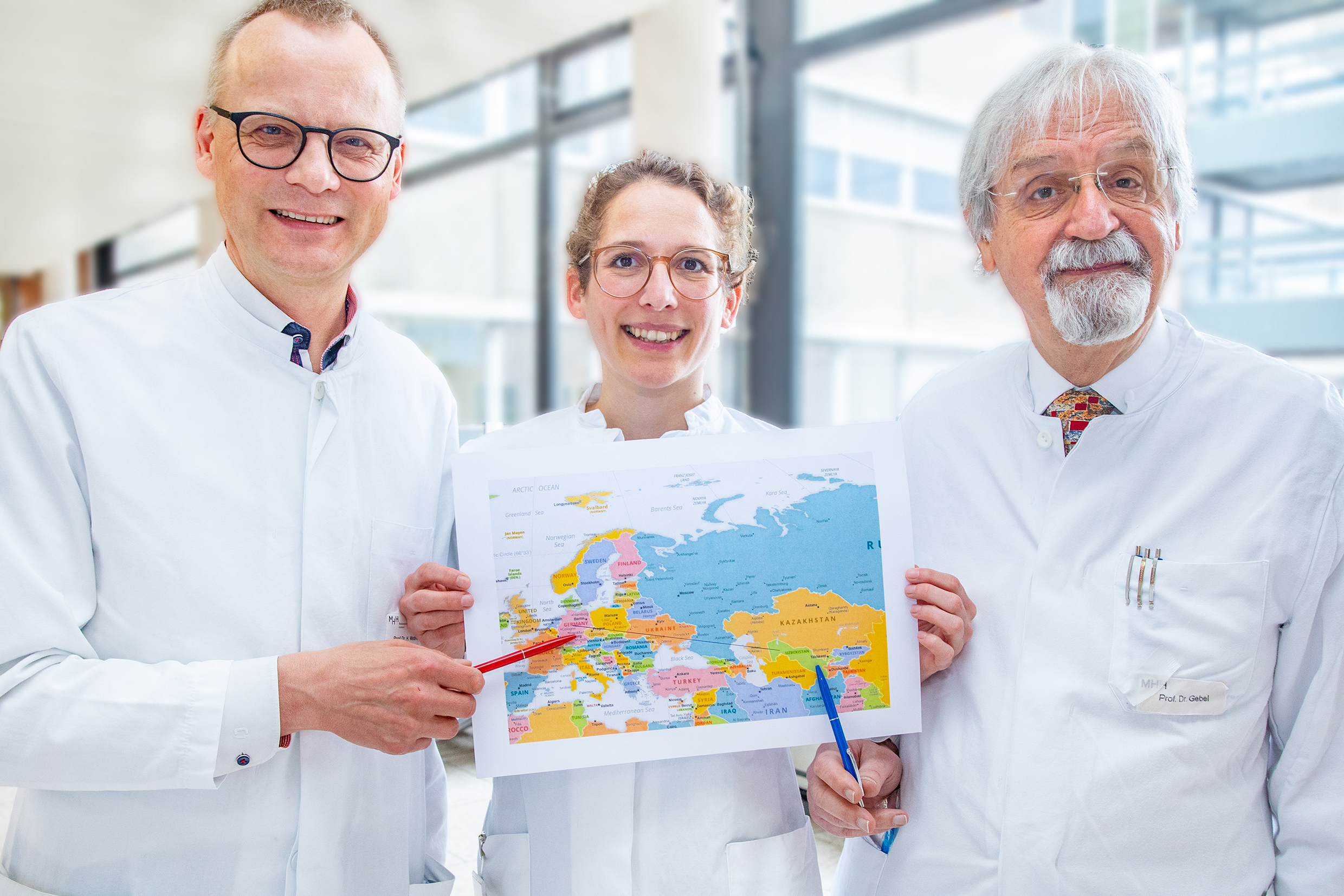 ): Professor Dr. Heiner Wedemeyer, Dr. Lisa Sandmann und Professor Dr. Michael Gebel zeigen auf einer Landkarte Deutschland und Usbekistan.