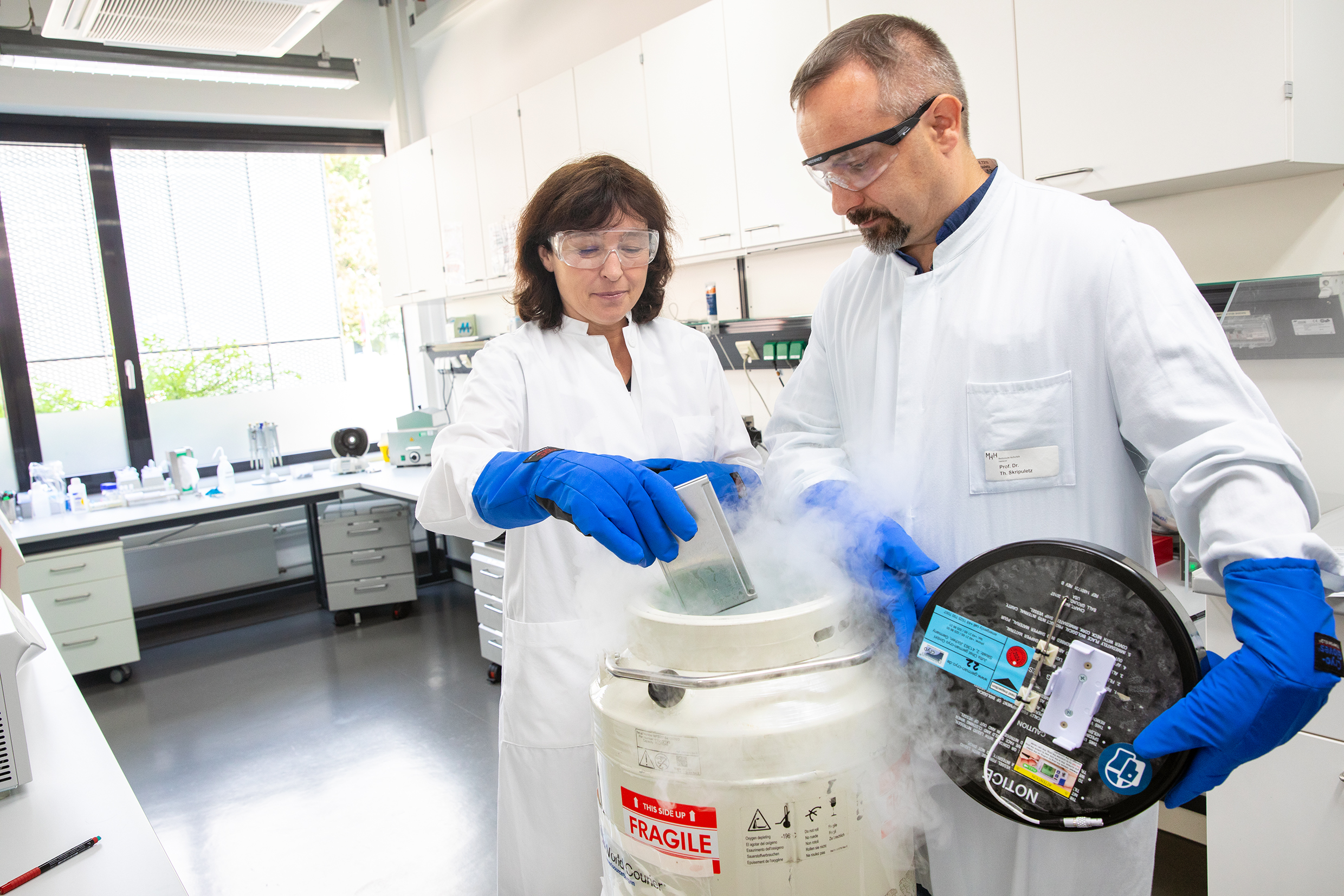 Professor Dr Britta Eiz-Vesper and Professor Dr Thomas Skripuletz take a pack of frozen T cells out of a special cryo container
